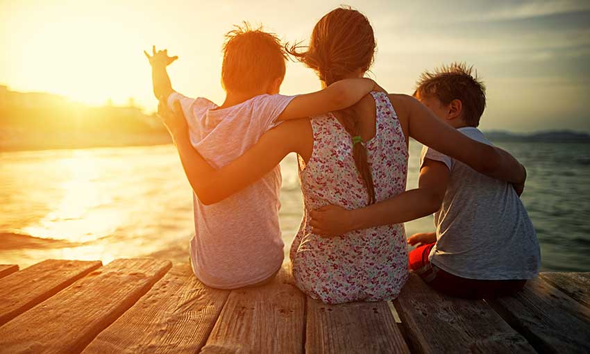 mum and sons sitting on a pier